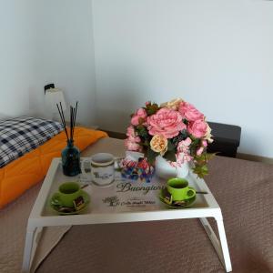 een tafel met bloemen en kopjes op een bed bij Il colle degli ulivi in San Calogero