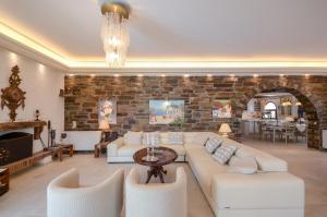 a living room with white furniture and a brick wall at Villa Pari Manda in Agios Prokopios
