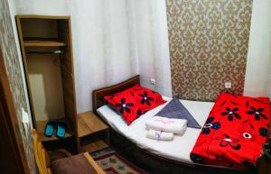 a small bedroom with a bed with red pillows at Hostel Violet in Tbilisi City