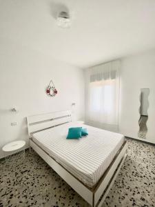 a white bedroom with a bed with blue pillows at Puntamare in Peschici