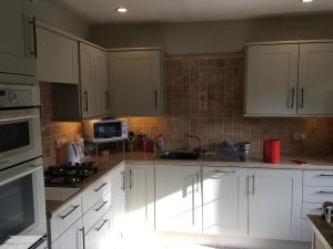 una cocina con armarios blancos y electrodomésticos blancos en Minehead mews cottage en Minehead