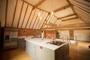 a large kitchen with white cabinets and a brick wall at Channels Retreat in Chelmsford
