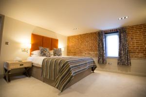 a bedroom with a bed and a brick wall at Channels Retreat in Chelmsford