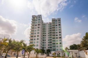 ein hohes Gebäude mit Palmen davor in der Unterkunft Magico Apartamento Frente al Mar 3 Habitaciones AR44 in Coveñas