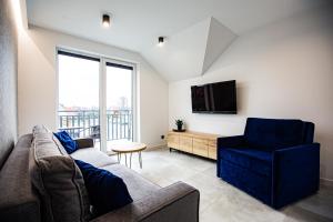 ein Wohnzimmer mit einem Sofa, einem TV und einem Stuhl in der Unterkunft Apart Family in Łeba
