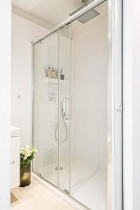 a glass shower stall in a bathroom with white walls at Ivory Apartment by LoftAffair in Krakow