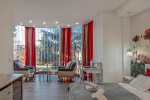 a bedroom with red curtains and a large window at Green Town Apartments in Sombor