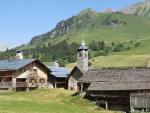 a church with a steeple and a mountain in the background at La Vardase in Le Grand-Bornand