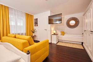 a living room with a yellow couch and a tv at Zum Fischer am See ***S in Prien am Chiemsee