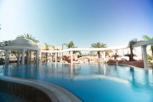 a swimming pool in a resort with trees and palm trees at Golf Residence By Sun and View in Eilat