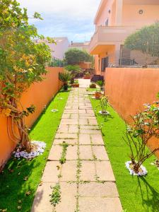 a garden with a stone path in front of a building at Piana Apartment in Carloforte