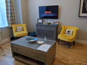 a living room with a tv and two yellow chairs at Heart of the City - FREE PARKING in York
