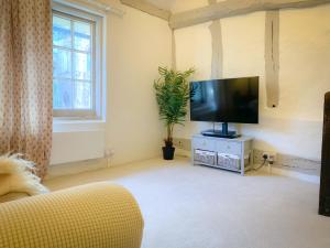 a living room with a flat screen tv and a couch at The Gate Cottage in Thaxted