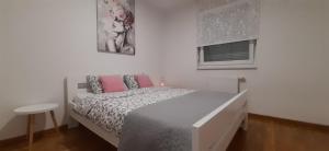 a white bedroom with a bed with pink pillows at Elena apartmani in Tuzla