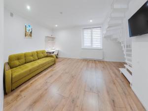 a living room with a yellow couch and a staircase at Antresol in Lviv