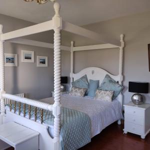1 dormitorio con cama blanca con dosel y almohadas azules en Stella Maris Luxury Bed and Breakfast, en Keel