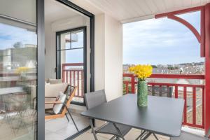 un tavolo con un vaso di fiori gialli su un balcone di Appartement de vacances en Cotes d Armor pour six personnes a Pléneuf-Val-André