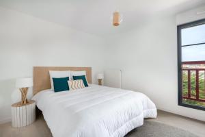 una camera bianca con un grande letto e una finestra di Appartement de vacances en Cotes d Armor pour six personnes a Pléneuf-Val-André