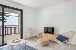- un salon avec une télévision, une table et des chaises dans l'établissement Un sejour en appartement face a la mer a Pleneuf Val Andre, à Pléneuf-Val-André