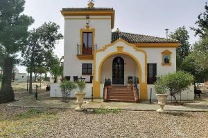 una pequeña casa blanca y amarilla con porche en Cortijo San José, en Sevilla