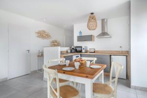 Una cocina con una mesa y sillas de madera. en Bel appartement pour 4 à 50m de la plage, en Pléneuf-Val-André