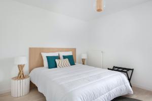 Un dormitorio con una gran cama blanca con almohadas azules. en Bel appartement pour 4 à 50m de la plage, en Pléneuf-Val-André