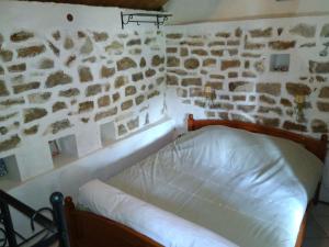 Bett in einem Zimmer mit einer Steinmauer in der Unterkunft Dependance du Moulin Galuzot in Saint-Vallier