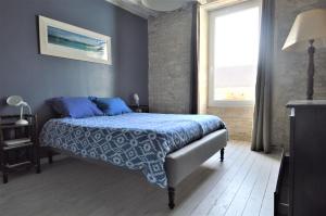 een slaapkamer met een bed met blauwe lakens en een raam bij Maison de charme bord de mer - Avec jardin et wifi in Luc-sur-Mer