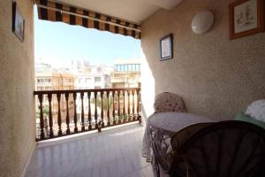 瓜爾達馬爾·德爾·塞古拉的住宿－Excelente apartamento vacacional en Guardamar a unos pasos de la playa, calle Paraguay，客房设有带窗户和椅子的阳台。