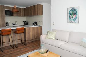 a living room with a white couch and a kitchen at Apartment - Kennedy - Parque Arauco in Santiago