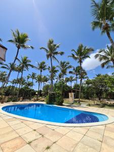 a swimming pool with palm trees in the background at Chalé 17 - Porto do Sol - Pipa in Pipa