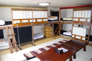 a room with several bunk beds and a table at P-Dash Garden Backpackers in Higashikawa