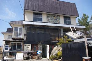 una casa con una valla negra delante de ella en P-Dash Garden Backpackers en Higashikawa