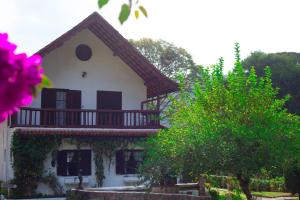 ein weißes Haus mit einem Balkon und einem Baum in der Unterkunft Pousada Taverna do Golf in Teresópolis
