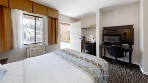 Recreation Inn and Suites في كيلونا: غرفة فندقية فيها سرير ومكتب وتلفزيون