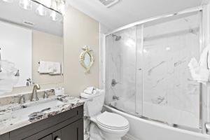 a white bathroom with a shower and a toilet and a sink at Costa Del Sol in Destin