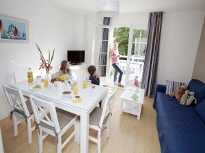 un soggiorno con tavolo bianco e 2 bambini seduti intorno di Résidence Odalys Le Domaine des Dunettes a Cabourg