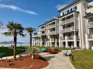 a large white building with palm trees in front of it at BalaLake Resort in Szántód