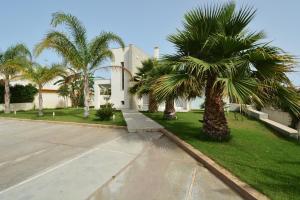 ein Haus mit Palmen vor einer Einfahrt in der Unterkunft Villa del Gelsomino in Punta Secca