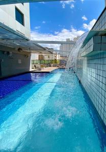 a swimming pool with a water fountain on the side of a building at Constantino Hotel e Eventos in Juiz de Fora