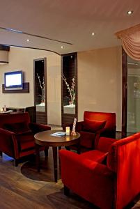 Una sala de estar con sillas rojas y una mesa. en Gazi Park Hotel, en Ankara
