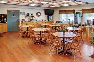 a dining room with tables and chairs and a kitchen at Coastal Inn Halifax - Bayers Lake in Halifax