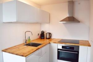 una cucina con mobili bianchi e un piano di lavoro in legno di Mooi vakantiehuis prachtig gelegen aan het water a Rijpwetering