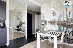 a dining room with a table and a painting of boats at MS Apartments Green Hill II in Gdynia