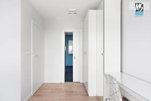 korytarz z białymi ścianami, drewnianymi podłogami i drzwiami w obiekcie MS Apartments Green Hill II w mieście Gdynia