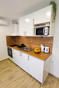 cocina con armarios blancos, fregadero y microondas en Apartman i studio apartman Vitana, en Garešnica