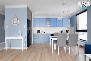 cocina con armarios azules, mesa y sillas en MS Apartments Matros, en Gdynia