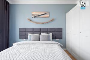 1 dormitorio con 1 cama grande y paredes azules en MS Apartments Matros, en Gdynia