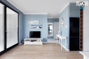 ein blaues Wohnzimmer mit einem TV und einem Schreibtisch in der Unterkunft MS Apartments Matros in Gdynia