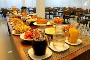 a long table with plates of food and drinks at Tupyguá Brasil Hotel in Pedro Leopoldo